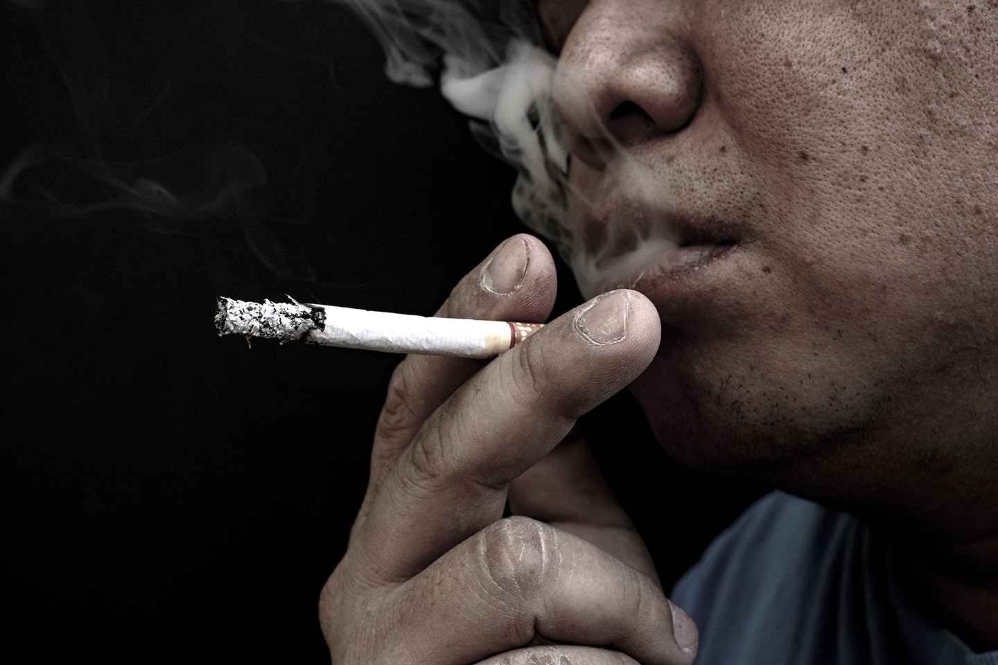 Man smoking a cigarette, Image of cigarette in hand with smoke